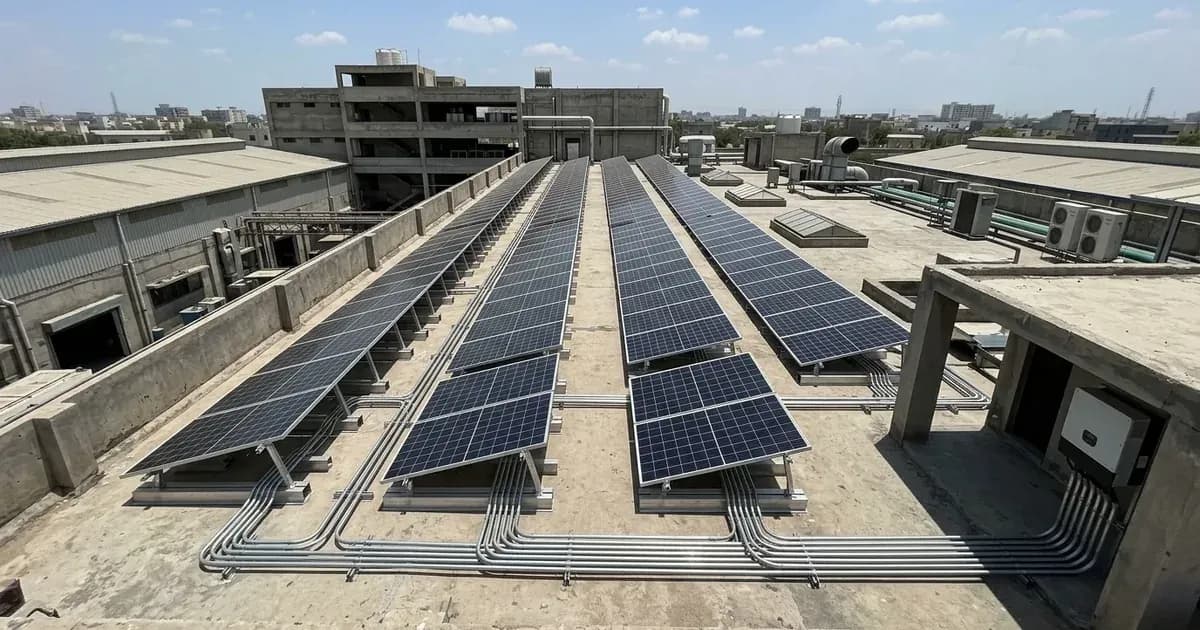 Commercial rooftop solar panel array installed on a factory building in Pakistan under bright daylight. — SolarNevs spec card