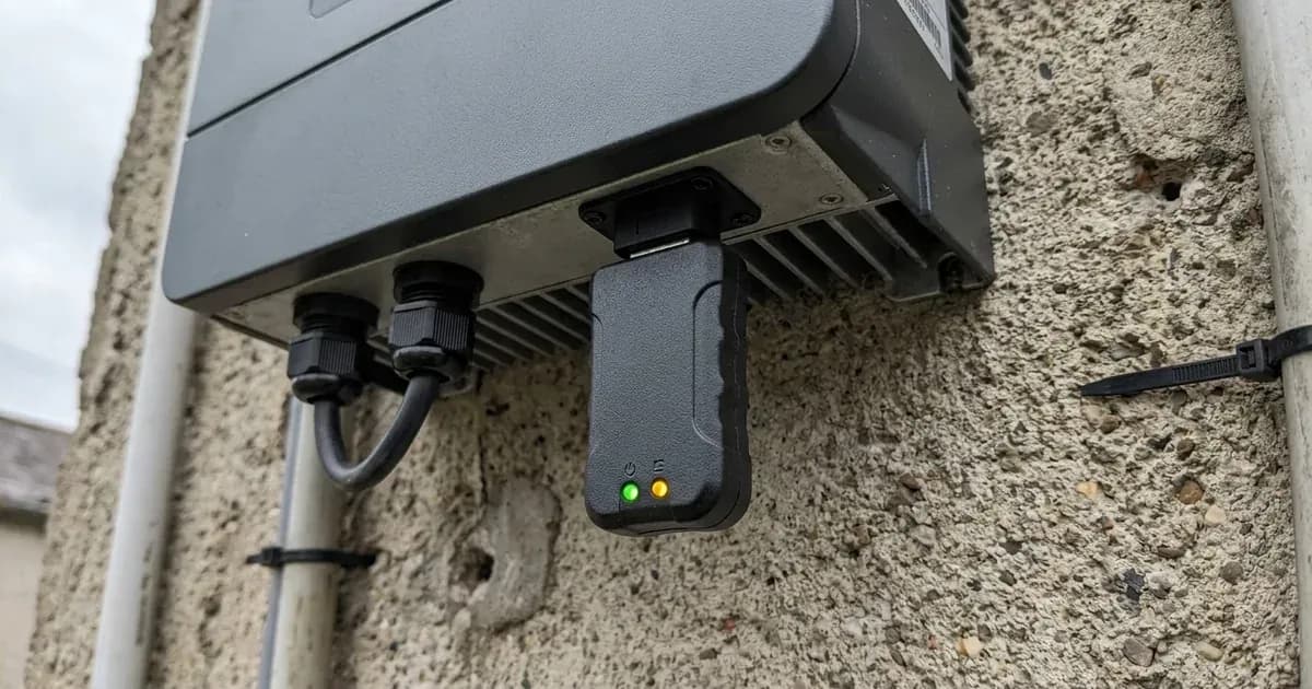 Unbranded Wi-Fi communication dongle with status LEDs plugged into a solar inverter on a concrete wall. — SolarNevs spec card