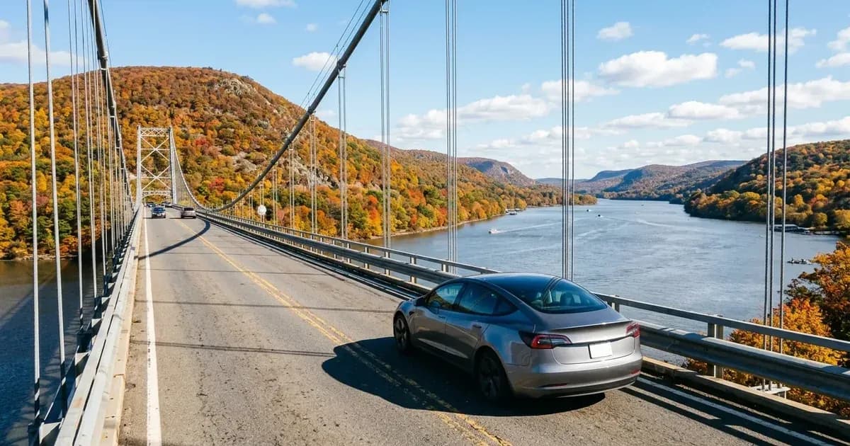 Electric car driving across a suspension bridge in New York's Hudson Valley surrounded by colorful autumn foliage. — SolarNevs spec card